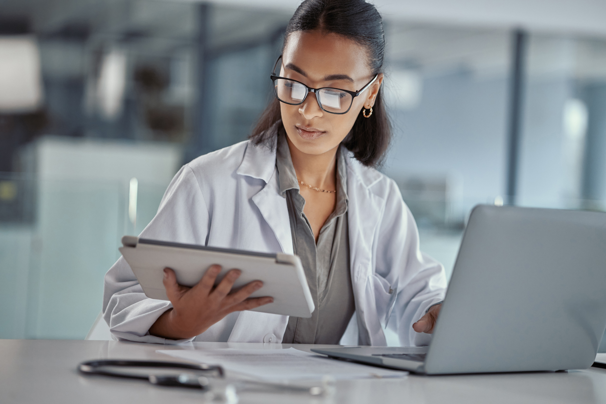 Clinician reviewing patient data on a tablet and laptop